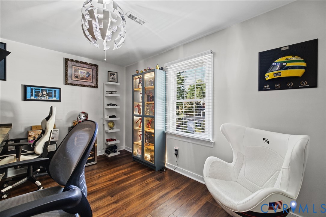 Room interior featuring wood-finish flooring, a multi-pane window with white horizontal blinds, and a contemporary geometric pendant light fixture