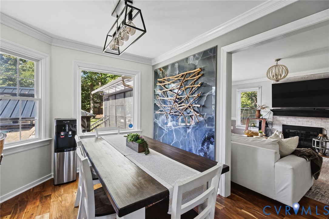 Dining area featuring wood-finish flooring, a geometric matte black pendant light, and large windows