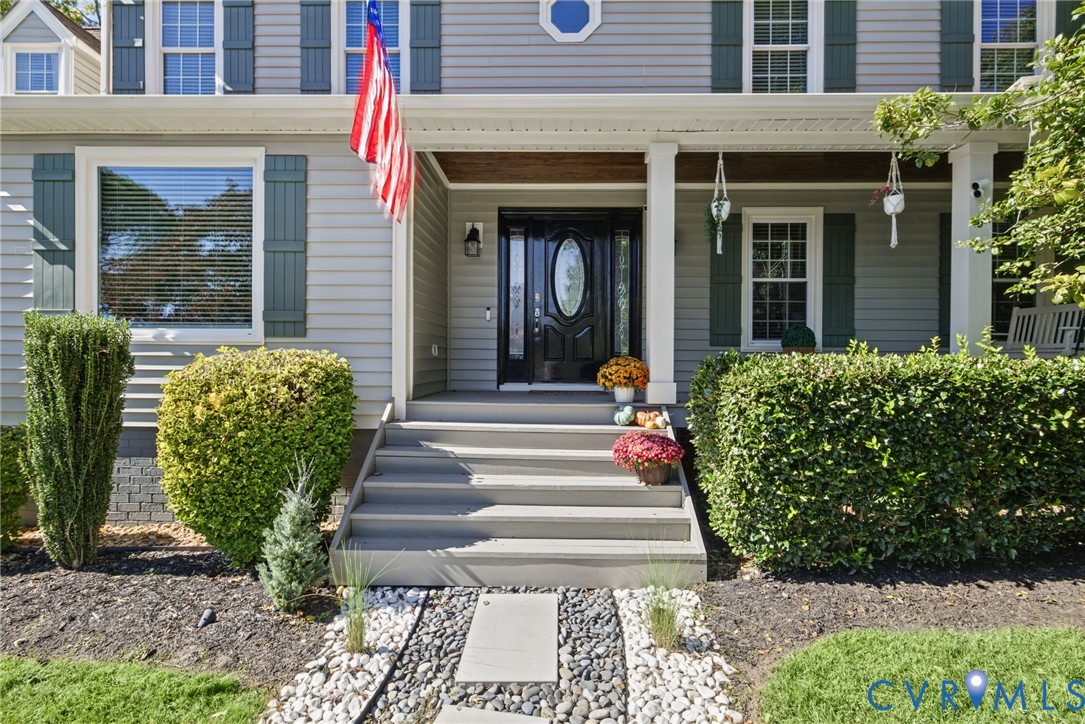 Exterior facade with horizontal siding and dark shutters, front porch featuring square columns and wood-tone ceiling, and a decorative front door with an oval glass inset