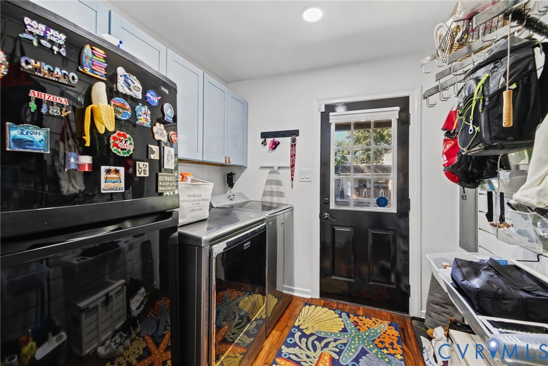 Laundry area featuring light-blue cabinetry, stainless steel laundry appliances, and an exterior door with a multi-pane glass insert