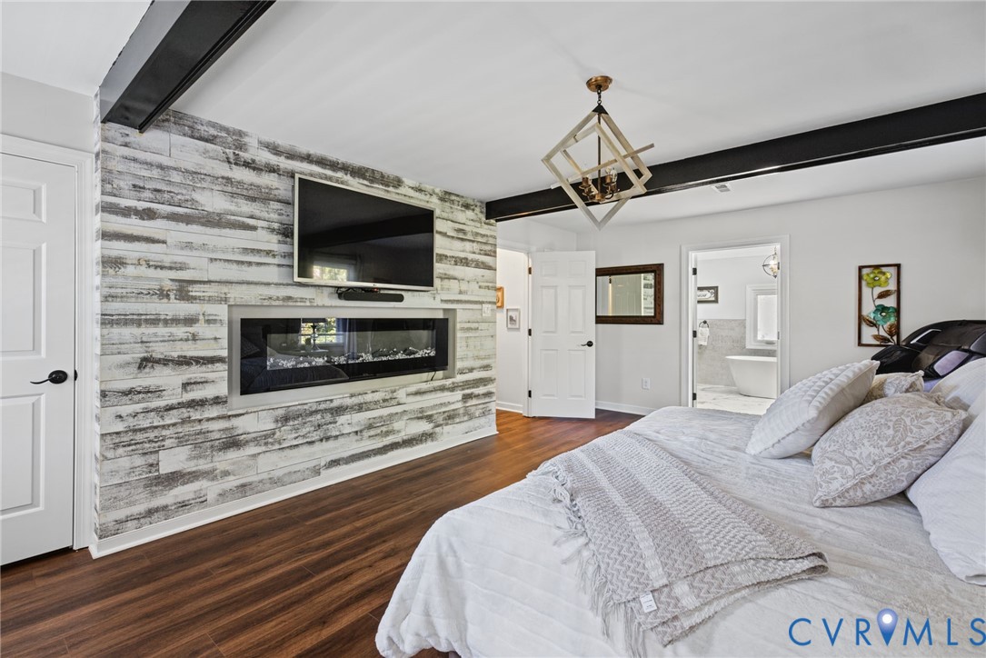 Weathered wood-finish accent wall with a built-in linear electric fireplace, exposed black structural beam, wood-finish flooring, and geometric metal-frame chandelier