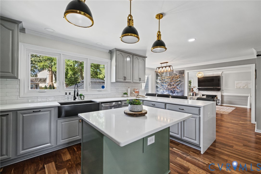 Kitchen featuring a central island with a quartz countertop, grey shaker-style cabinetry, a deep farmhouse sink with a matte black faucet, and pendant lighting