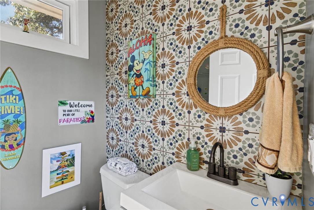 Patterned ceramic tile accent wall, vessel sink with matte black faucet, and fixed transom window