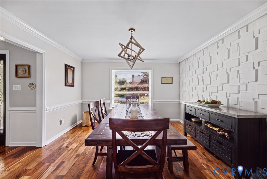 Textured geometric accent wall, wood-finish flooring, crown molding, chair rail trim, and custom geometric pendant light fixture
