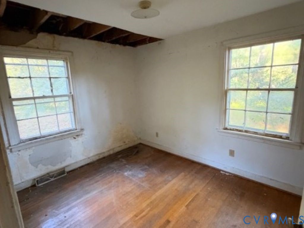 Room featuring wood-finish flooring, two multi-pane windows, and a semi-flush mount ceiling fixture