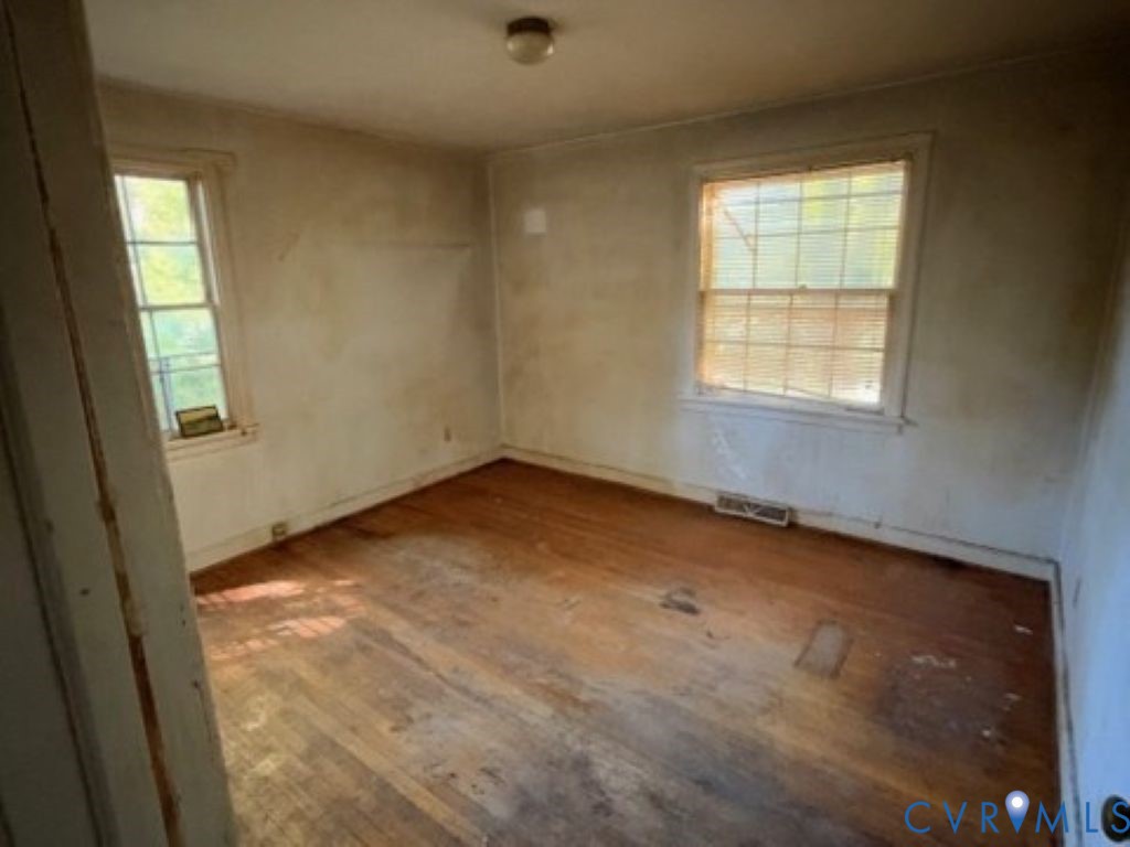 Room featuring wood-finish flooring, two multi-pane windows, and a ceiling-mounted light fixture