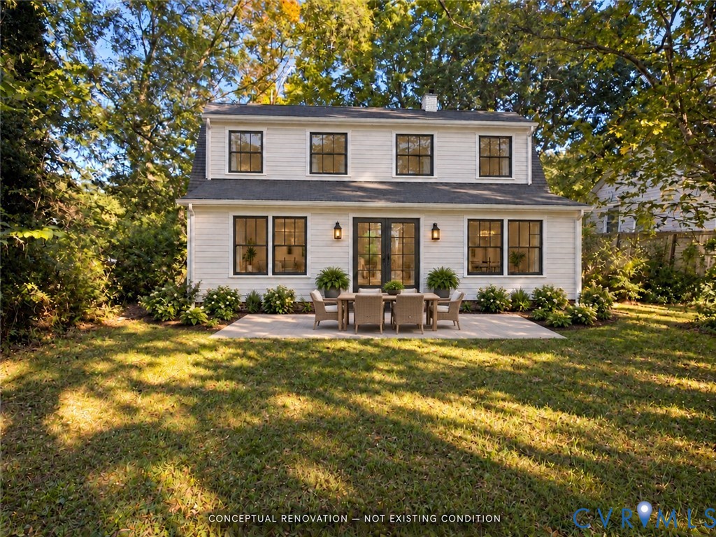 Two-story residence featuring light-toned horizontal siding, dark-trimmed grid windows, dual-panel glass French doors, and a stone patio