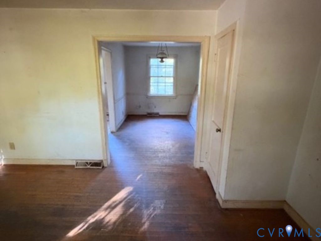 Interior featuring wood flooring, single-pane window, and wooden door with hardware