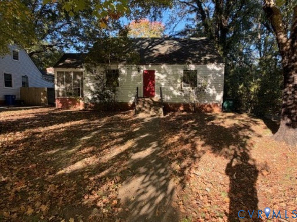 Single-story residence featuring light-colored horizontal siding, a red front door, brick foundation, and an enclosed porch