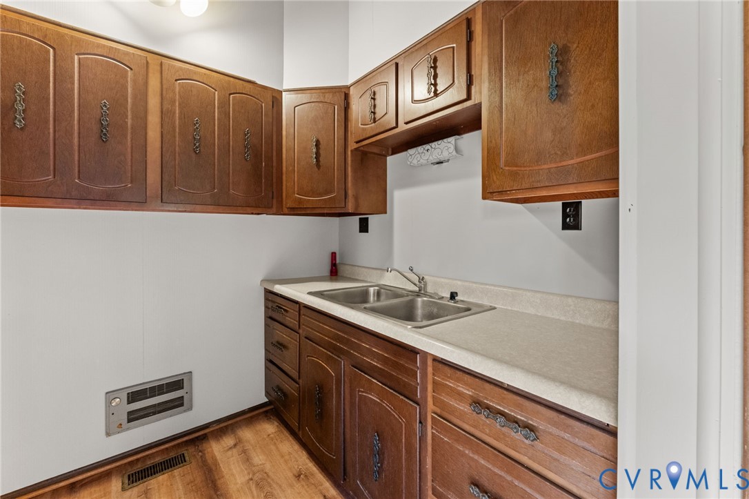 Kitchen has Double sinks, wood cabinets & laminate flooring.