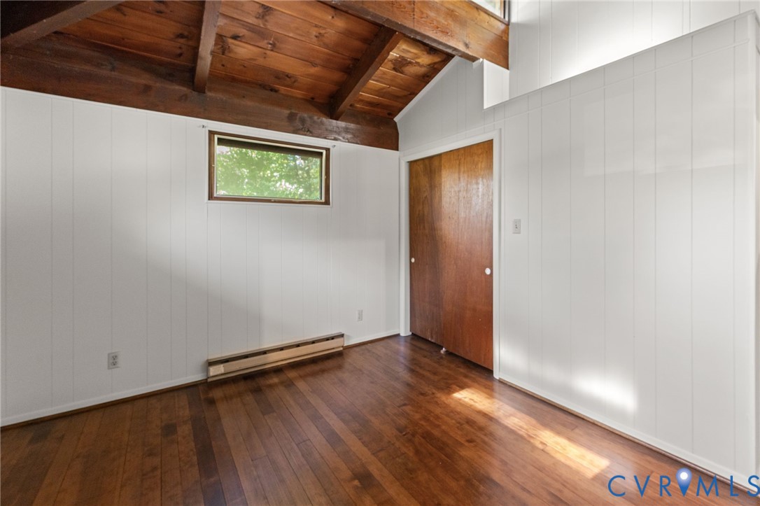 Primary Bedroom with vaulted, exposed cedar-beamed ceiling, wood floors & half Bath.