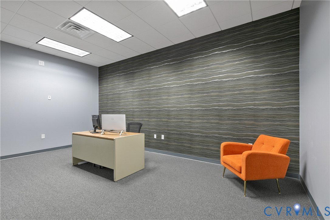 Room featuring a statement accent wall with textured horizontal-patterned wall covering, neutral carpeting, and recessed rectangular lighting fixtures