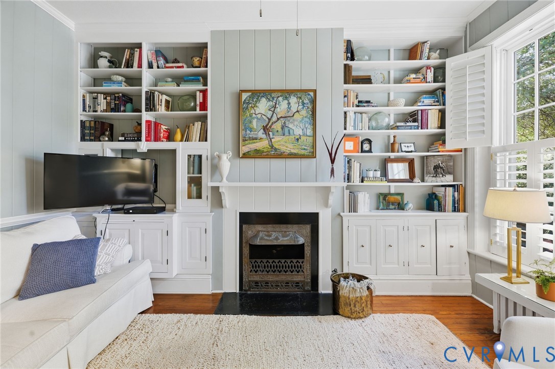 Fireplace with a metal insert and dark hearth flanked by floor-to-ceiling built-in cabinetry with integrated shelving and base cabinets