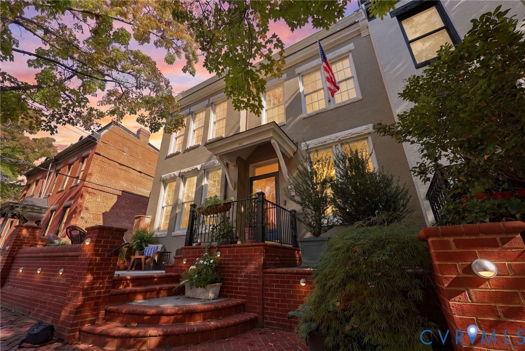 Brick exterior facade featuring a covered entryway, elevated porch with metal railings, and tiered red brick stairs Brick exterior facade featuring a covered entryway, elevated porch with metal railings, and tiered red brick stairs