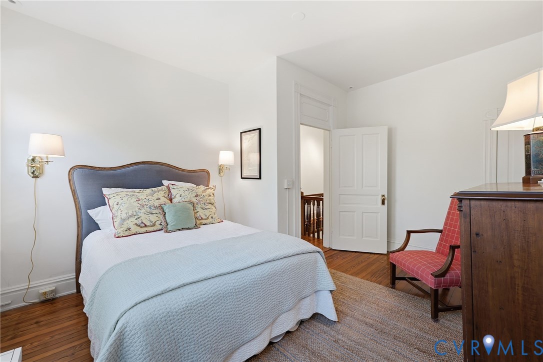 Hardwood flooring, two wall-mounted adjustable sconces, and a multi-panel interior door