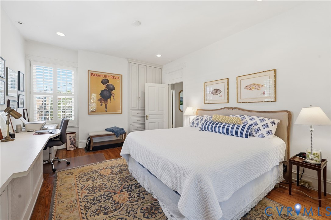 Built-in floor-to-ceiling cabinetry, custom desk surface, wood-finish flooring, recessed lighting, and white plantation shutters