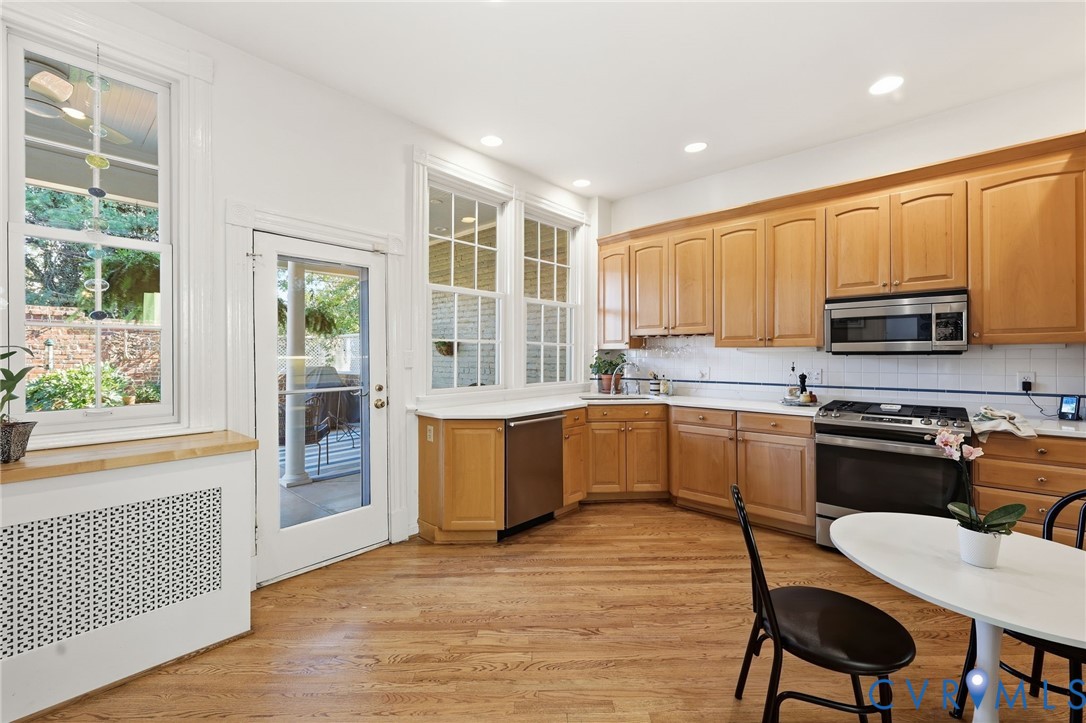 Kitchen featuring wood cabinetry, stainless steel appliances, wood-finish flooring, recessed lighting, and multi-pane windows