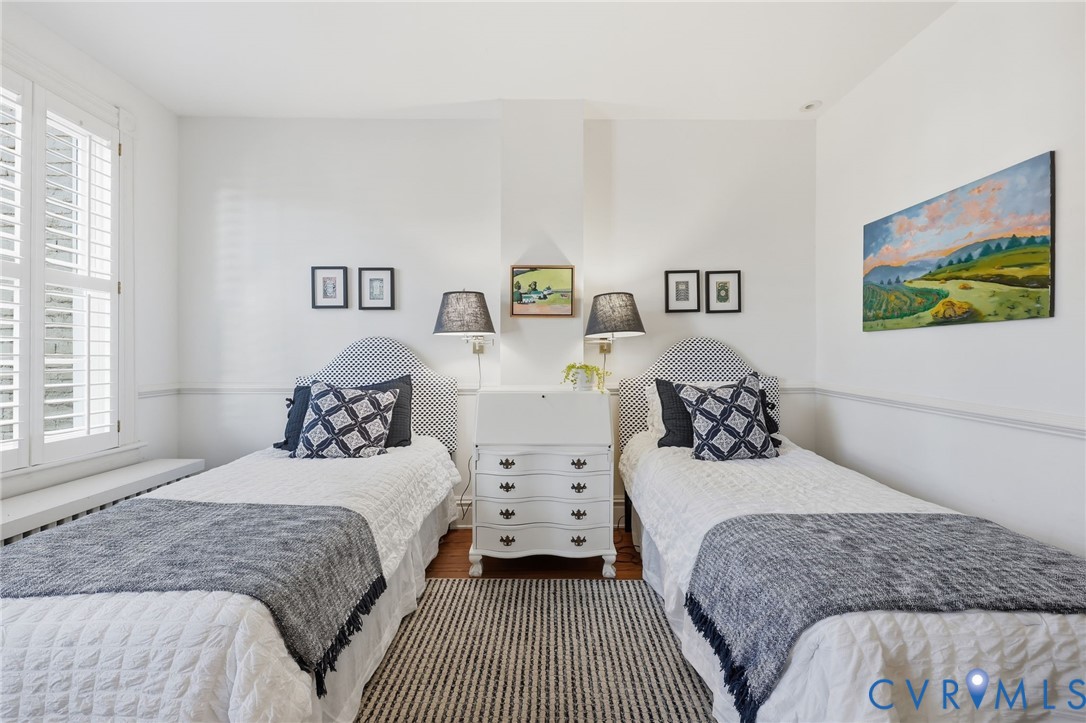 Interior room featuring hardwood flooring, white wall-mounted chair rail, and white louvered shutters