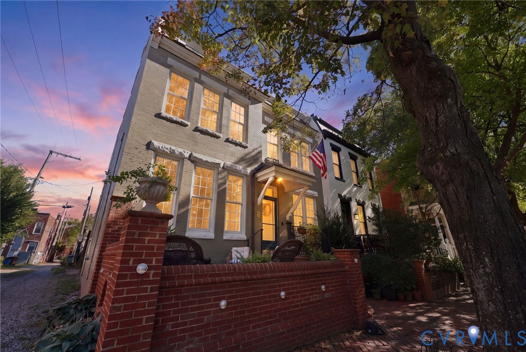 Three-story masonry exterior featuring a front brick terrace, multi-pane windows, and a covered entryway