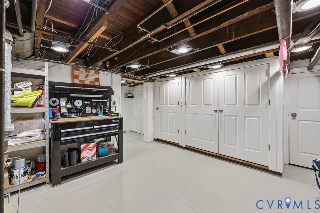 Utility area featuring an epoxy-coated concrete floor, exposed wood-joist ceiling, recessed lighting, and multiple interior six-panel doors