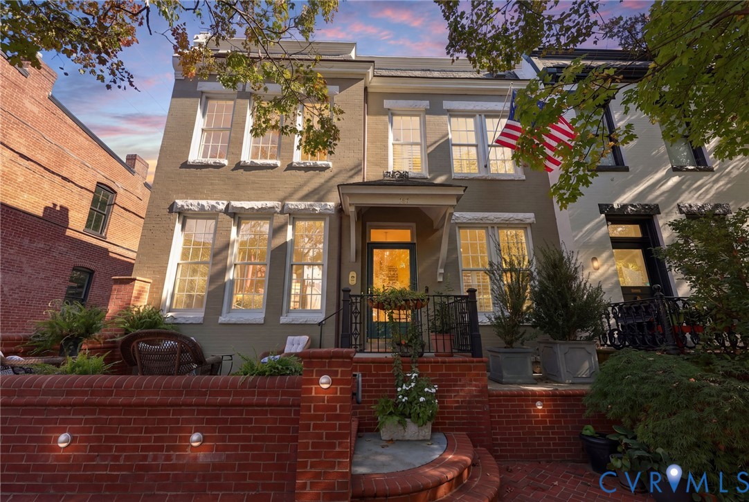 Multi-story masonry exterior featuring a raised brick terrace, covered entryway, and multi-pane windows