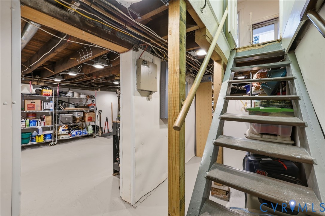 Unfinished lower level featuring exposed wood joist ceilings, concrete flooring, and a wooden staircase