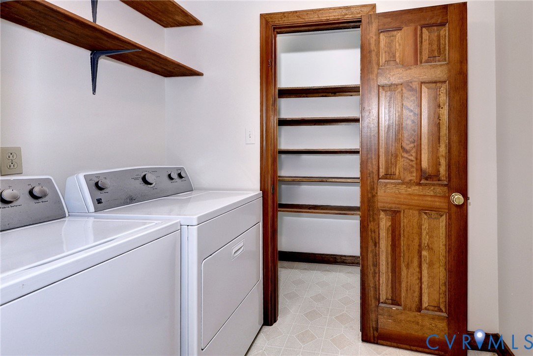 Utility room featuring wall-mounted wood shelving, a six-panel wood door, and a built-in pantry with multiple tiers of shelving