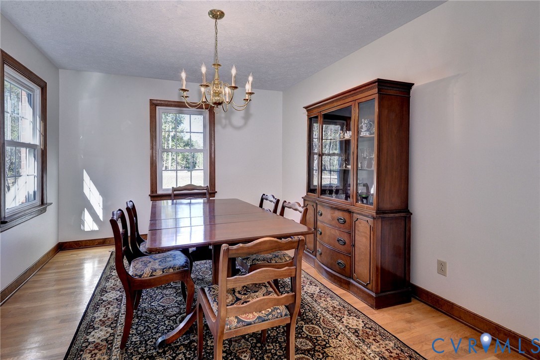 Dining area featuring wood-finish flooring, multi-pane windows with wood trim, and a multi-arm metallic chandelier