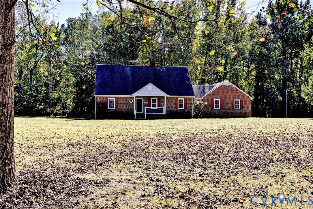 Brick exterior residence featuring a front porch, gabled roofline, decorative shutters, and expansive acreage
