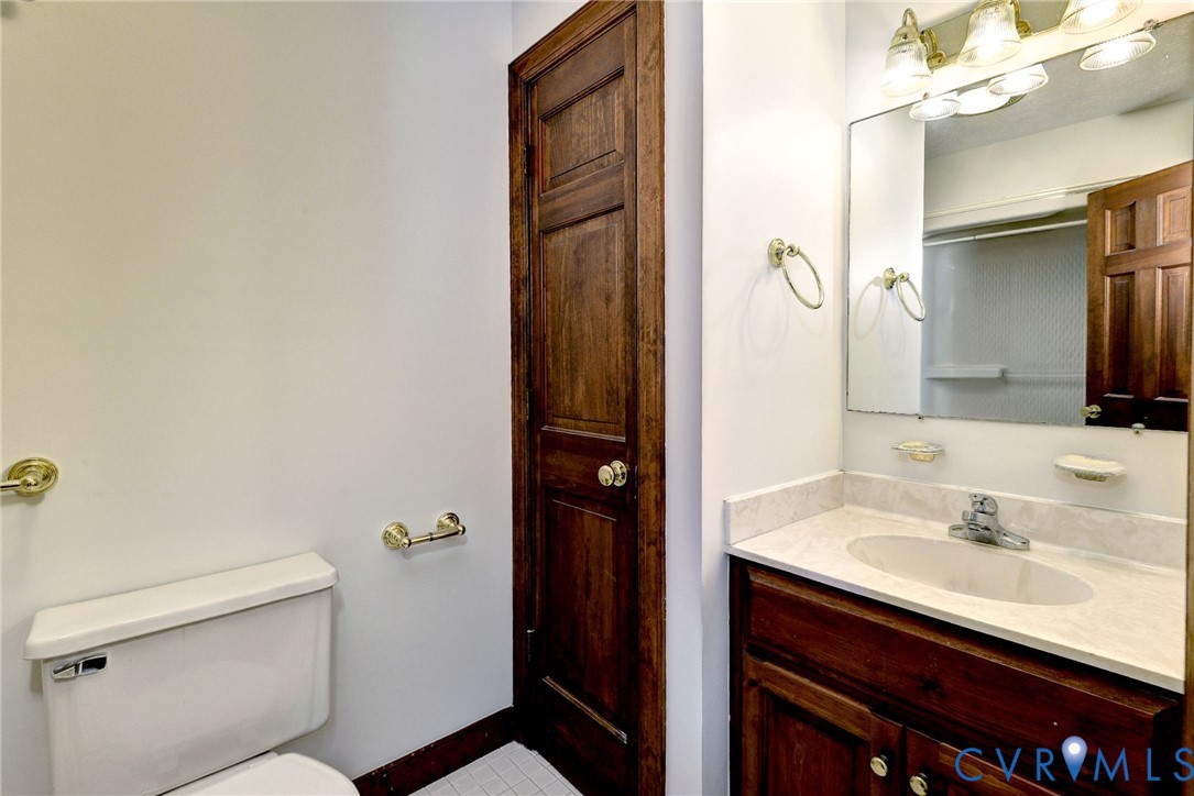Vanity featuring a stone-composite countertop with an integrated oval basin, natural wood-finish cabinetry, solid wood door, and polished brass fixtures
