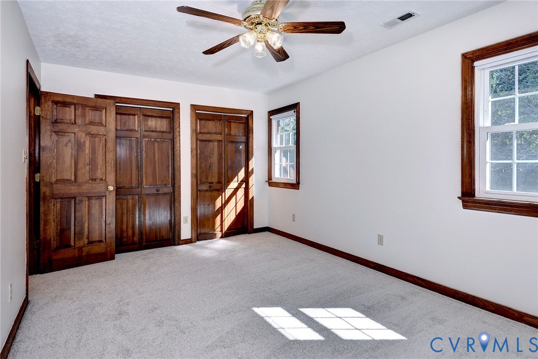 Neutral carpeting, natural wood-finish interior doors and trim, double-hung windows, and a ceiling fan with integrated lighting