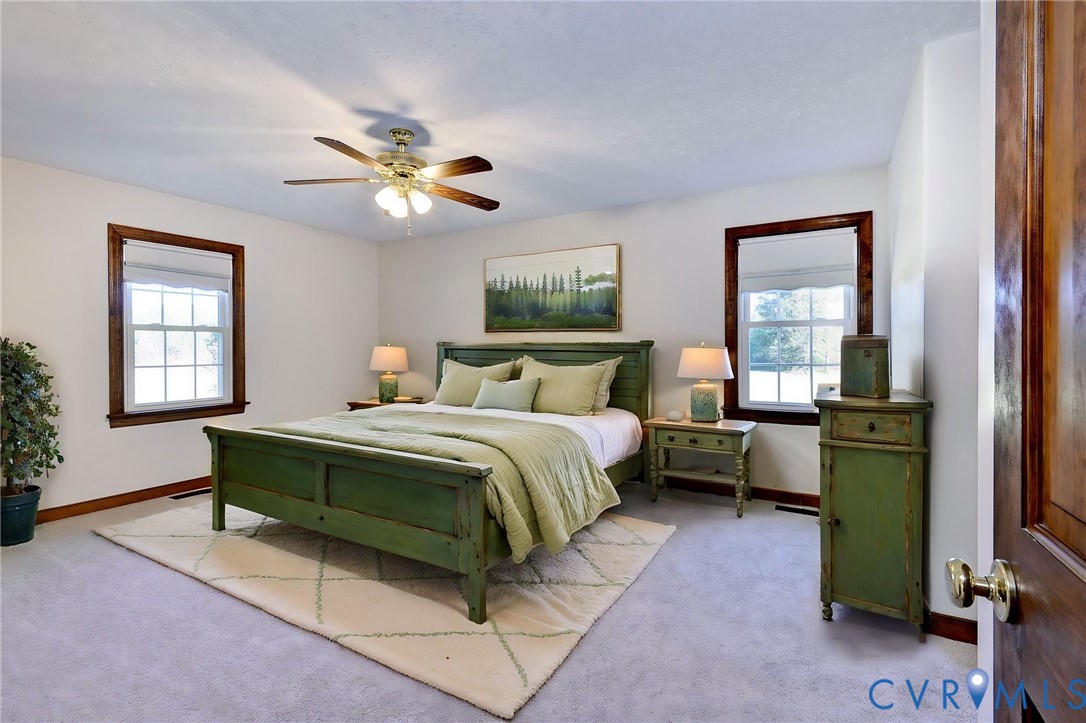 VIRTUAL STAGING - Dual windows with dark wood trim, integrated ceiling fan with light fixture, and solid wood interior door