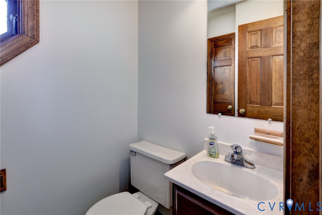 Vanity featuring a stone-composite countertop, oval undermount sink, chrome faucet, and wood-finish cabinetry, paired with a wood-framed mirror