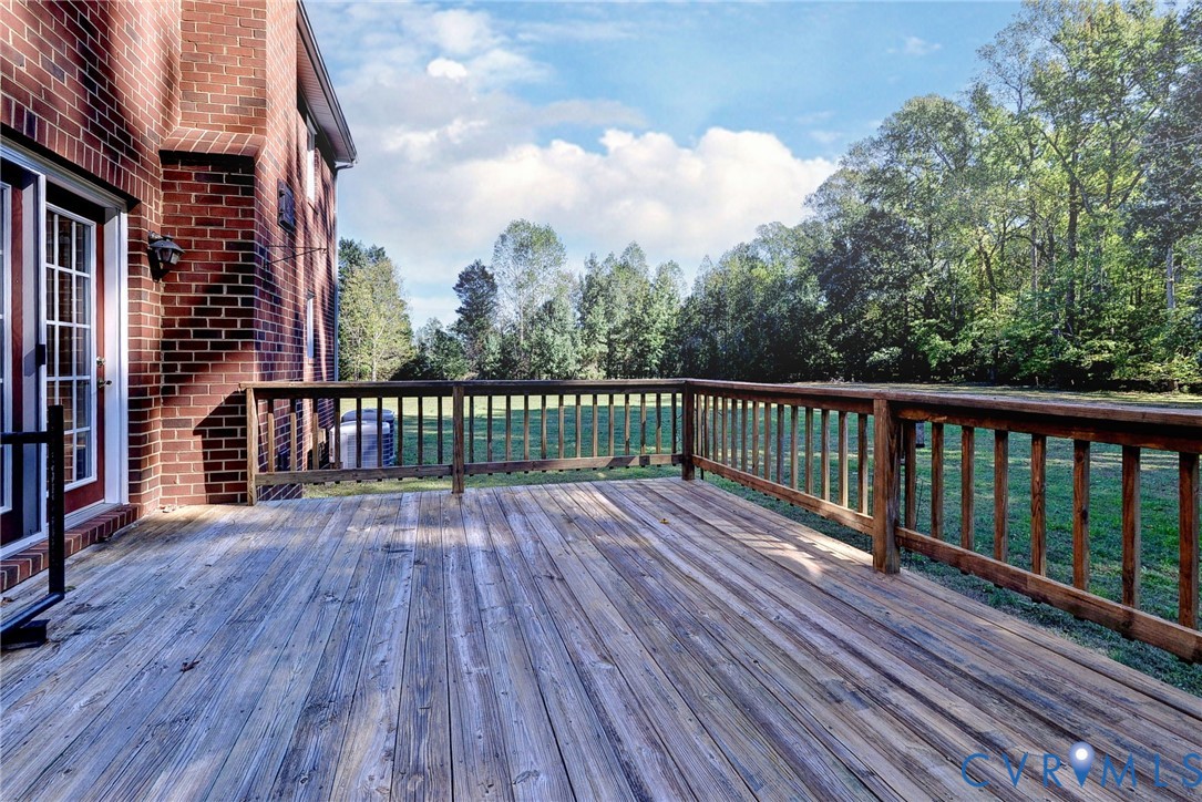 Exterior wood deck featuring a railing and brick home siding