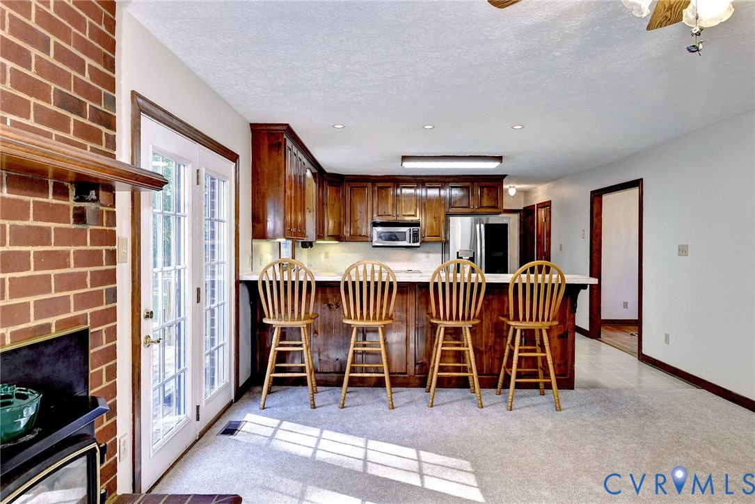 Kitchen featuring wood cabinetry, breakfast bar with countertop seating, recessed lighting, and glass-paned doors leading to exterior