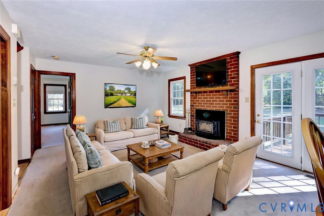 -VIRTUAL STAGING Red brick fireplace with a wood-burning insert and timber mantel, floor-to-ceiling glass-paneled double doors, and wood-finish trim throughout