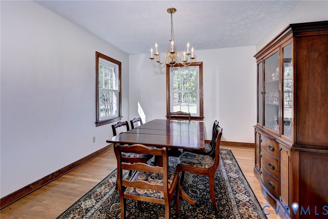 Dining area featuring hardwood flooring, wood-framed windows, a built-in wooden china cabinet, and a multi-arm chandelier