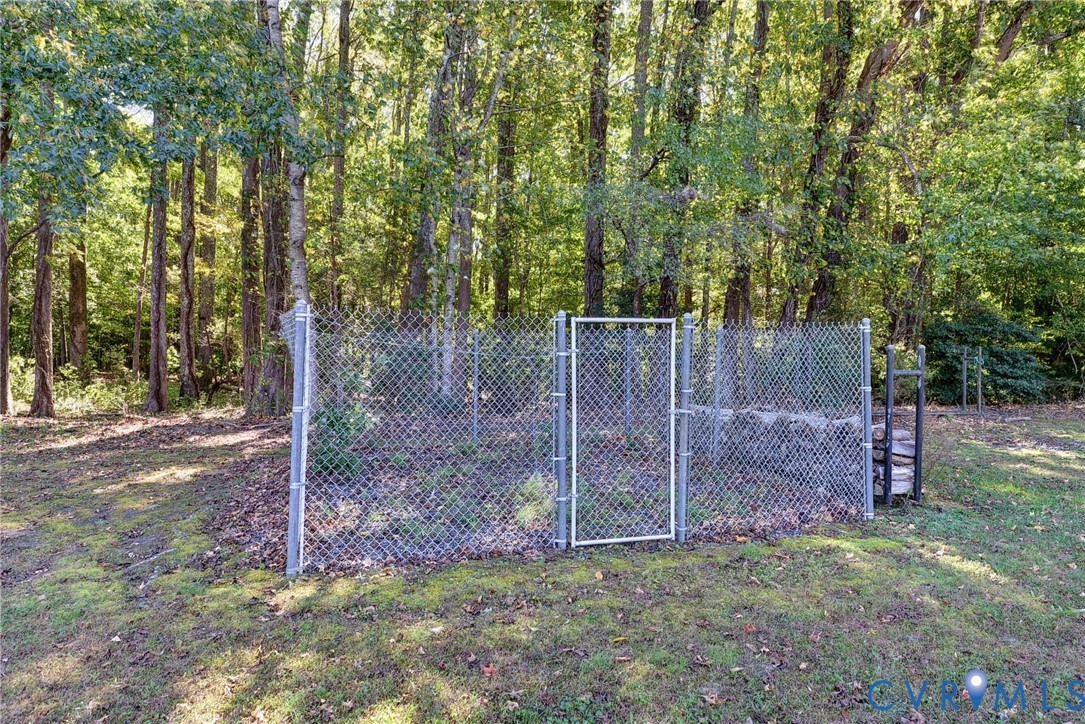 Chain-link perimeter fencing surrounding a natural lot with mature tree growth