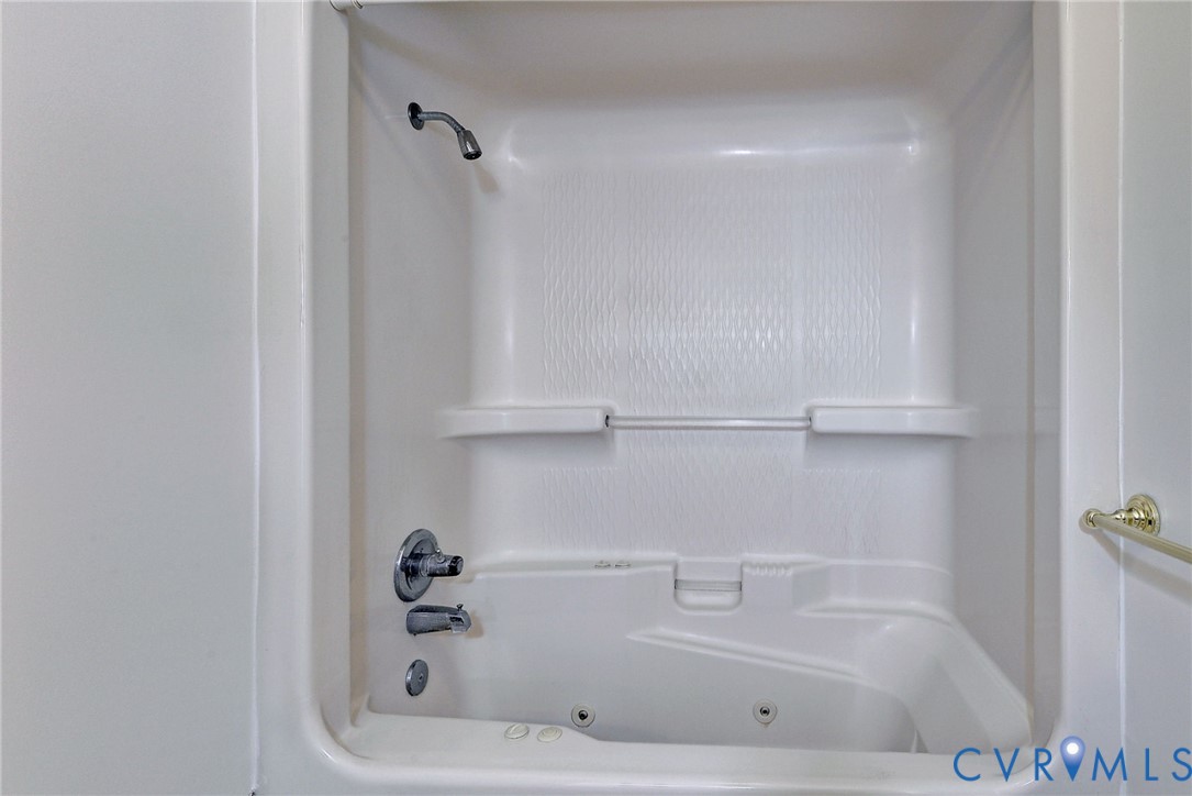 Recessed tub and shower combination featuring molded shelving, integrated jetted tub system, and metallic plumbing fixtures