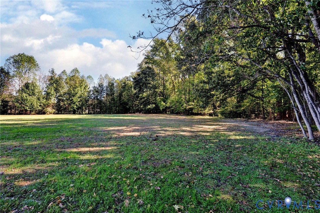 Expansive open lot featuring level terrain, cleared grassy areas, and mature tree borders