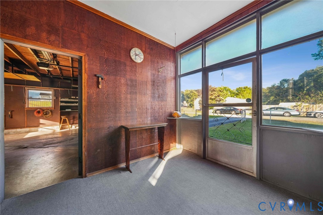 Enclosed area featuring wood-panelled walls, floor-to-ceiling windows, and direct access to an attached garage Enclosed area featuring wood-panelled walls, floor-to-ceiling windows, and direct access to an attached garage