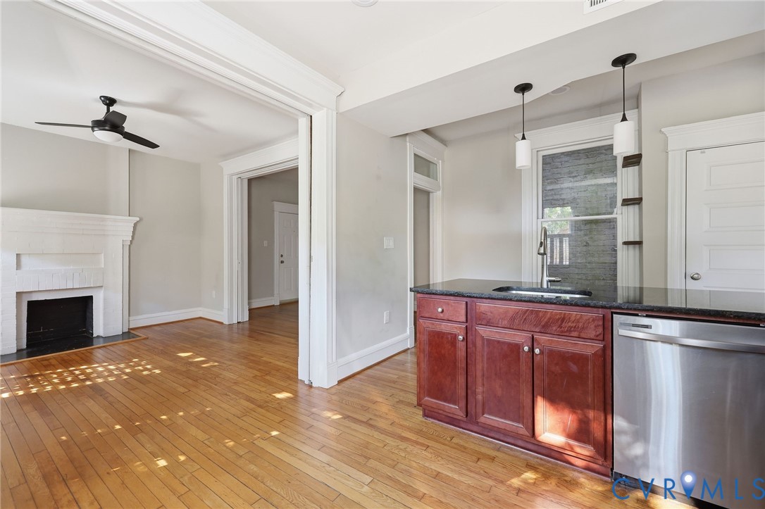 Kitchen featuring dark cabinetry, stone-finish countertops, stainless steel dishwasher, and pendant lighting