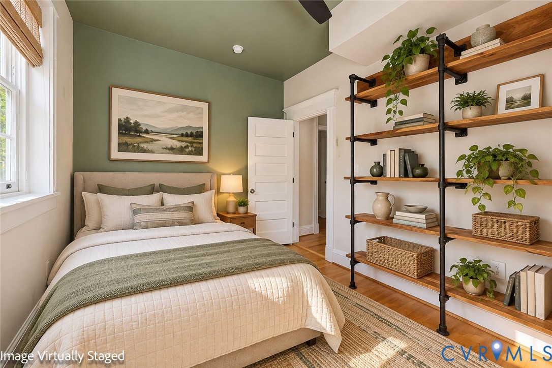 Built-in floor-to-ceiling industrial-style shelving featuring dark metal pipe supports and natural wood-finish shelving, accented by a deep olive-green ceiling and wall color, traditional five-panel interior door, and hardwood flooring