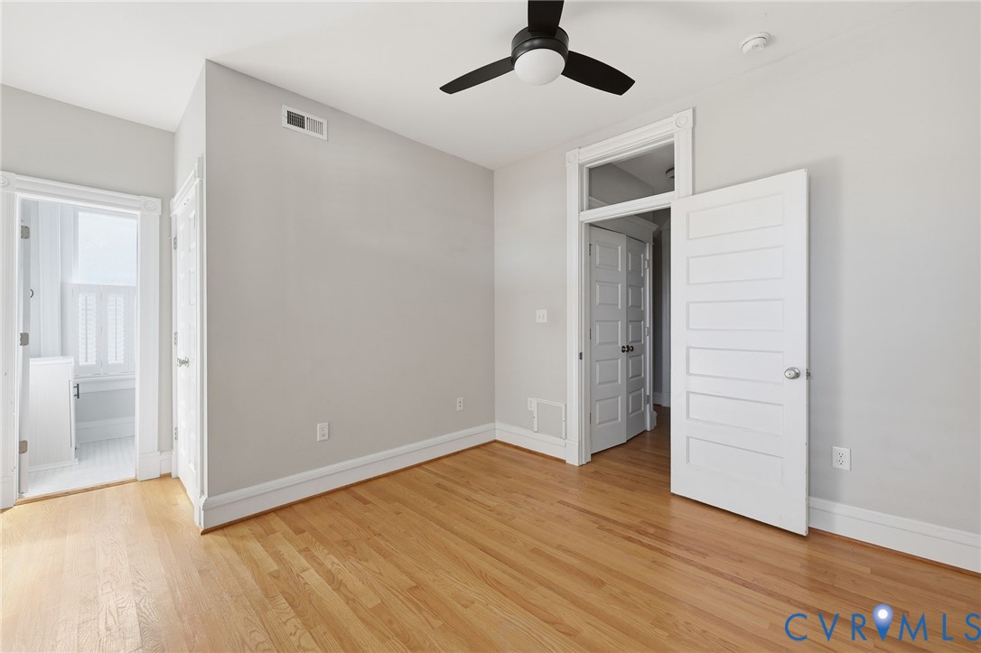 Interior space featuring wood-finish flooring, a ceiling fan with integrated lighting, multi-panel doors, and a transom window