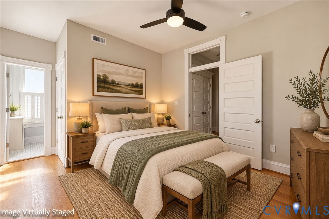 Wood-finish flooring, high ceilings with an integrated ceiling fan, and multi-panel interior doors with transom windows