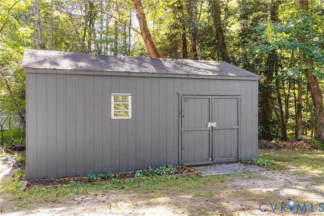 Standalone storage shed featuring vertical siding, dual swing doors, and a single window