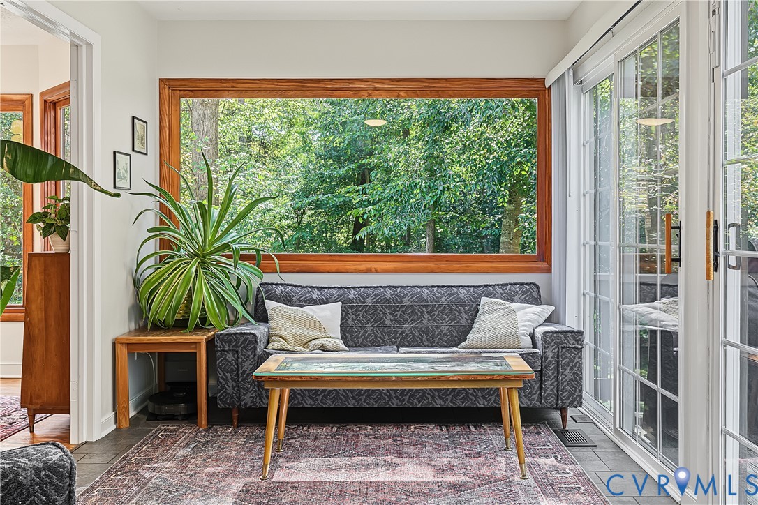 Large picture window with wood trim, slate-style flooring, and sliding glass doors