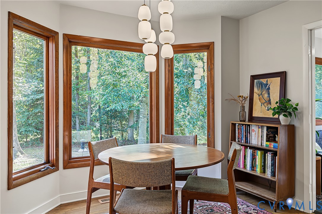Bay window featuring natural wood-trimmed casement windows, wood-finish flooring, and a multi-pendant modern light fixture