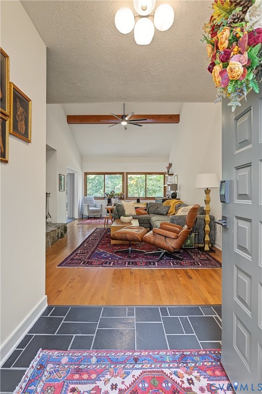Entryway featuring slate tile flooring, wood-finish flooring, vaulted ceilings, and a decorative exposed structural wood beam Entryway featuring slate tile flooring, wood-finish flooring, vaulted ceilings, and a decorative exposed structural wood beam