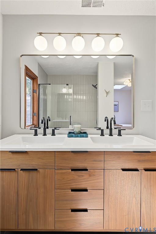 Dual-sink vanity featuring wood-finish cabinetry, rectangular integrated basins, matte black widespread faucets, and a broad rectangular mirror illuminated by a five-globe fixture